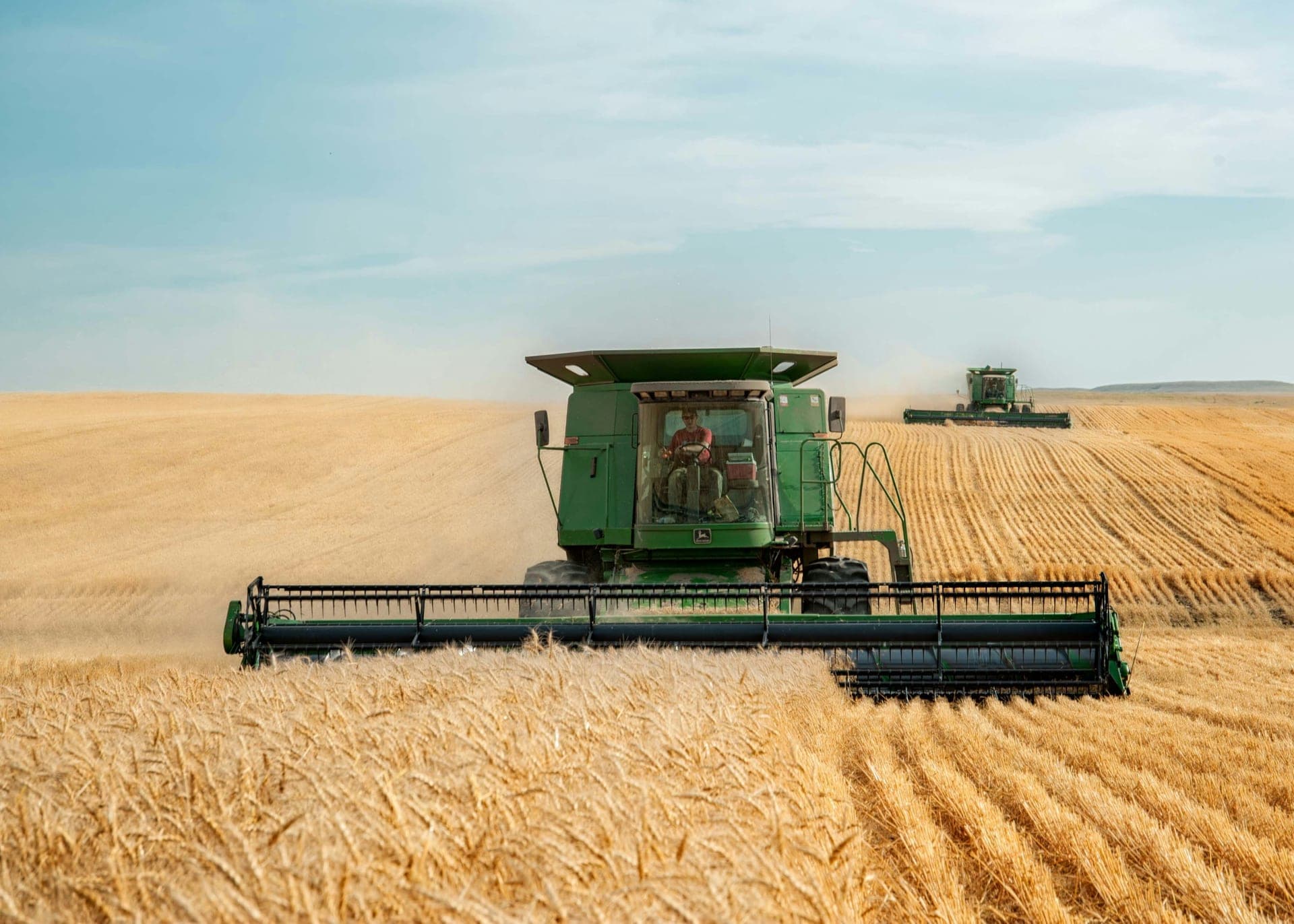 John Deere harvesters working in a wheat field - business finance broker for Australian farmers and regional businesses