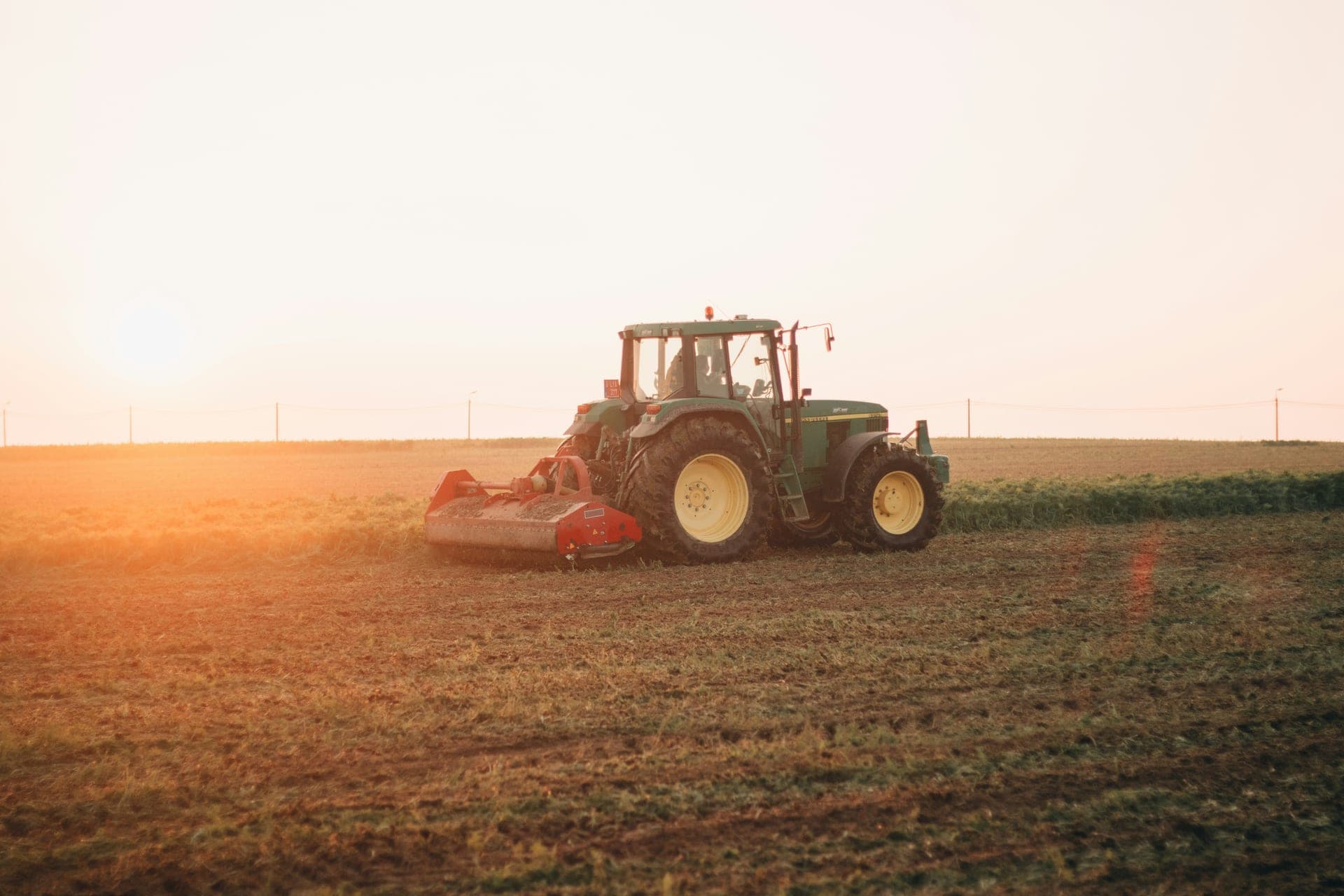 Tractor plowing a field at golden sunset in Narrandera NSW - agricultural equipment finance for Australian farmers
