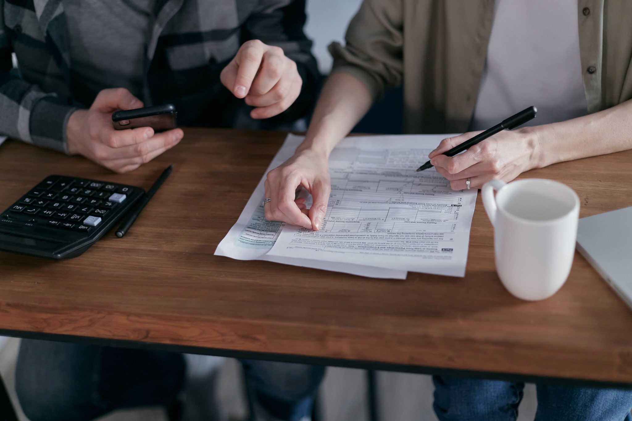 Couple reviewing a document with calculator, phone and coffee on a table